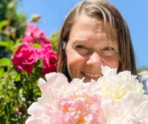 A photo of the author with blooming roses and peonies.